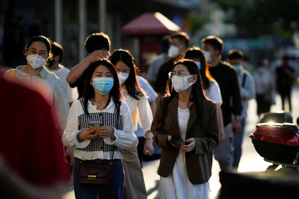 People wearing protective face masks walk on a street, after the lockdown placed to curb COVID-19 spread was lifted in Shanghai on June 7, 2022. (Aly Song/Reuters)