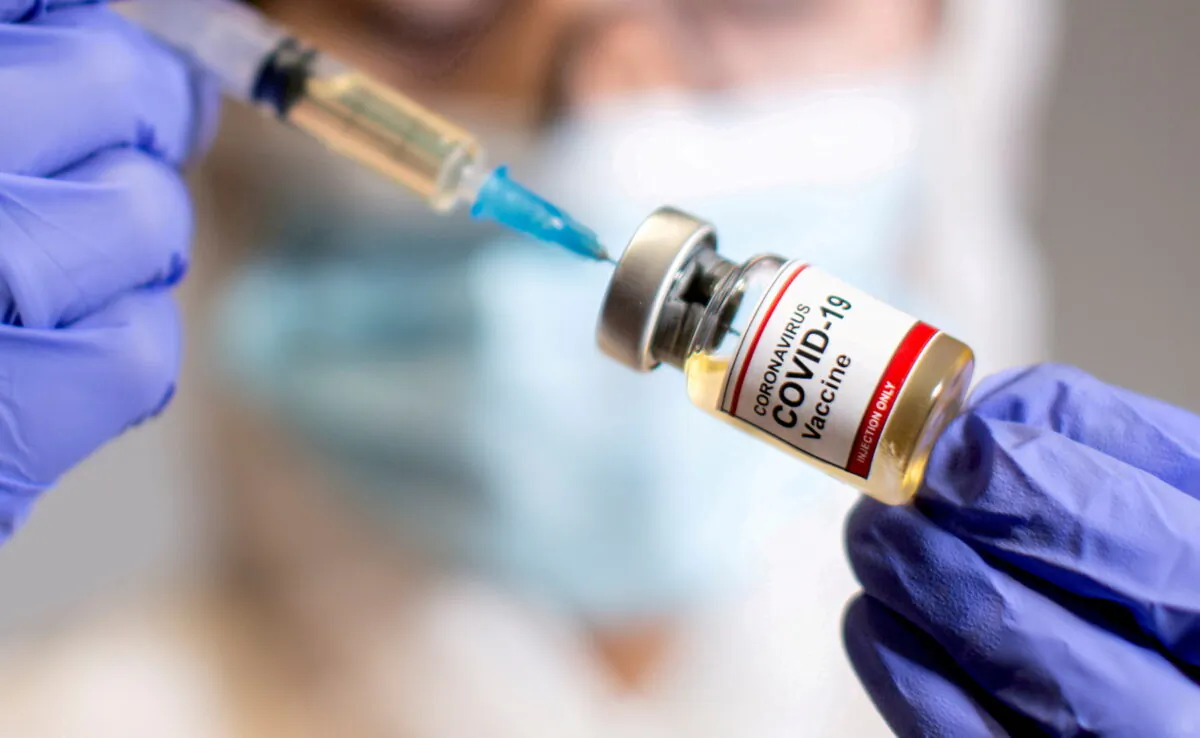 A woman holds a small bottle labelled with a "Coronavirus COVID-19 Vaccine" and a medical syringe in this illustration taken Oct. 30, 2020. (Dado Ruvic/Reuters)