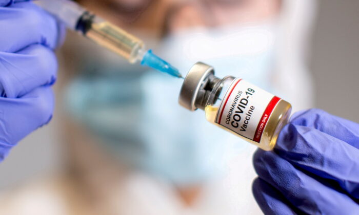 A woman holds a small bottle labelled with a "Coronavirus COVID-19 Vaccine" and a medical syringe in this illustration taken Oct. 30, 2020. (Dado Ruvic/Reuters)