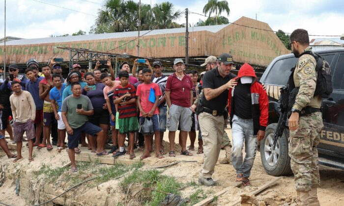 Federal Police officers escort a man accused to be involved in the missing of British journalist Dom Phillips and indigenous expert Bruno Pereira, who went missing while reporting in a remote and lawless part of the Amazon rainforest, near the border with Peru, in Atalaia do Norte, Amazonas state, Brazil, on June 15, 2022. (Bruno Kelly/Reuters)