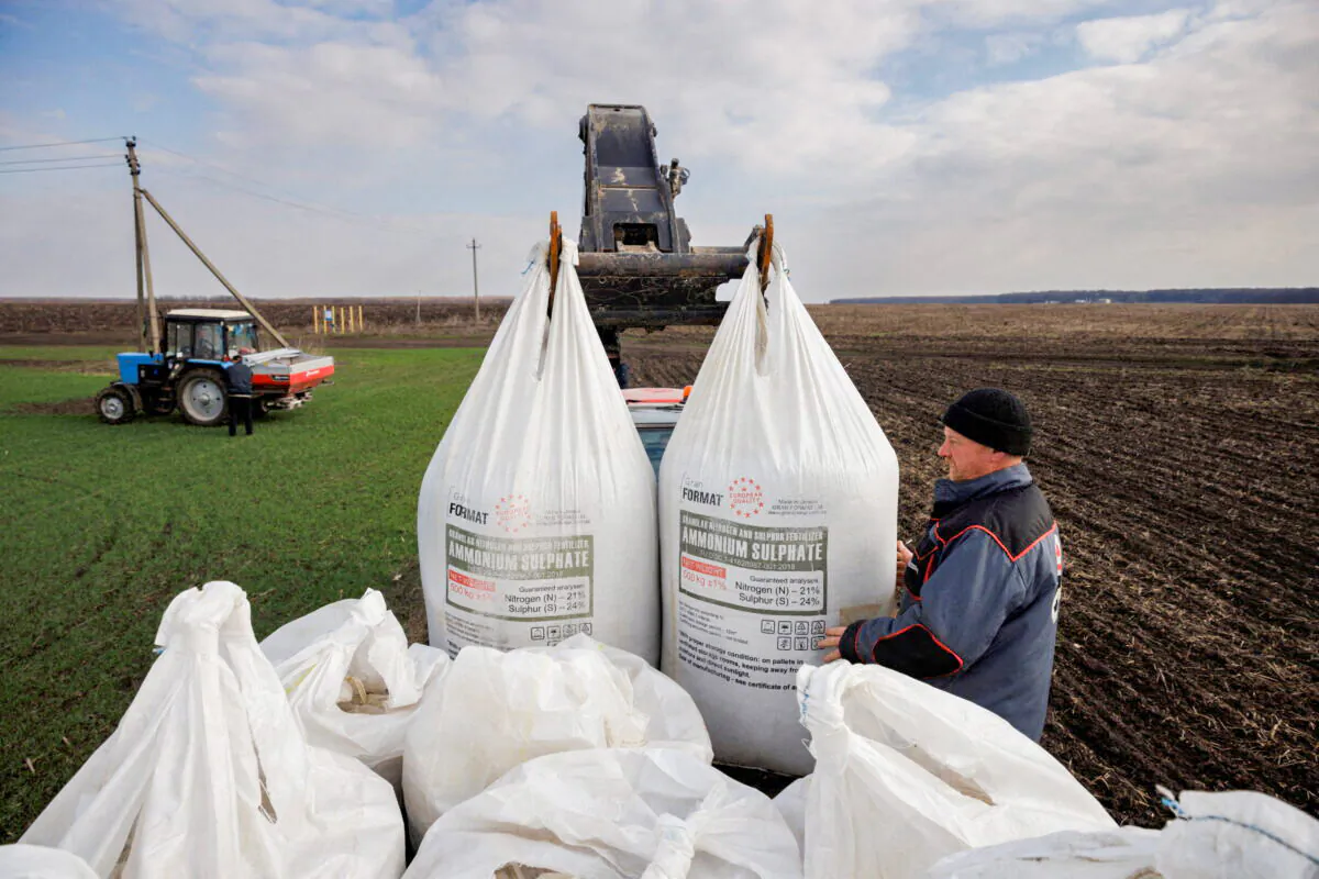 A local farm worker unloads Ukrainian-made fertilizer from a truck to use on a wheat field near the village of Yakovlivka after it was hit by an aerial bombardment outside Kharkiv, Ukraine, on April 5, 2022, as Russia's attack on Ukraine continues. (Thomas Peter/Reuters)