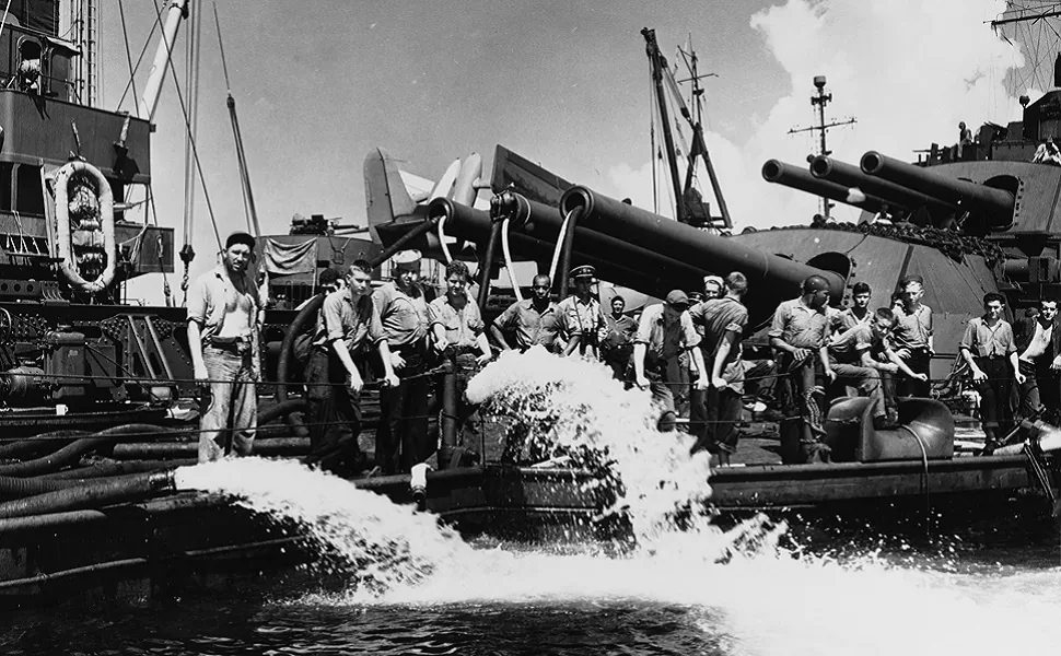 Sailors of the battleship U.S.S. Pennsylvania (BB-38) pump out water over her quarterdeck, after being torpedoed in Buckner Bay, Okinawa, on Aug. 12. (Naval History and Heritage Command)
