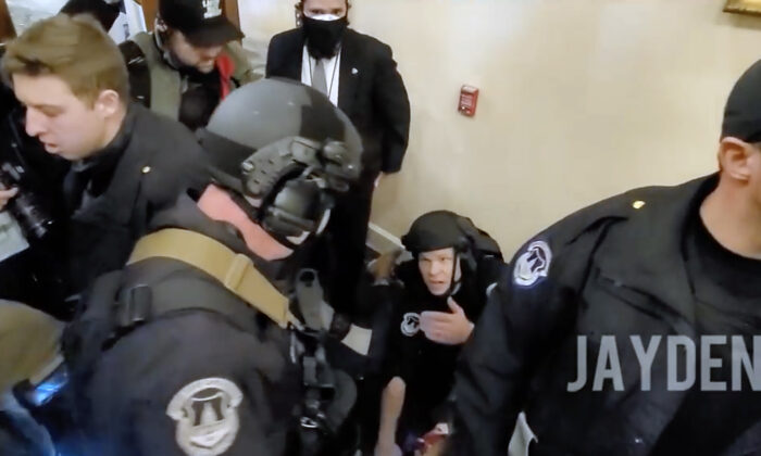 U.S. Capitol Police Officer Steven Robbs kneels over Ashli Babbitt just after she was shot by Lt. Michael Byrd in the hallway outside the Speaker's Lobby on January 6, 2021. (JaydenX/Screenshot via The Epoch Times)