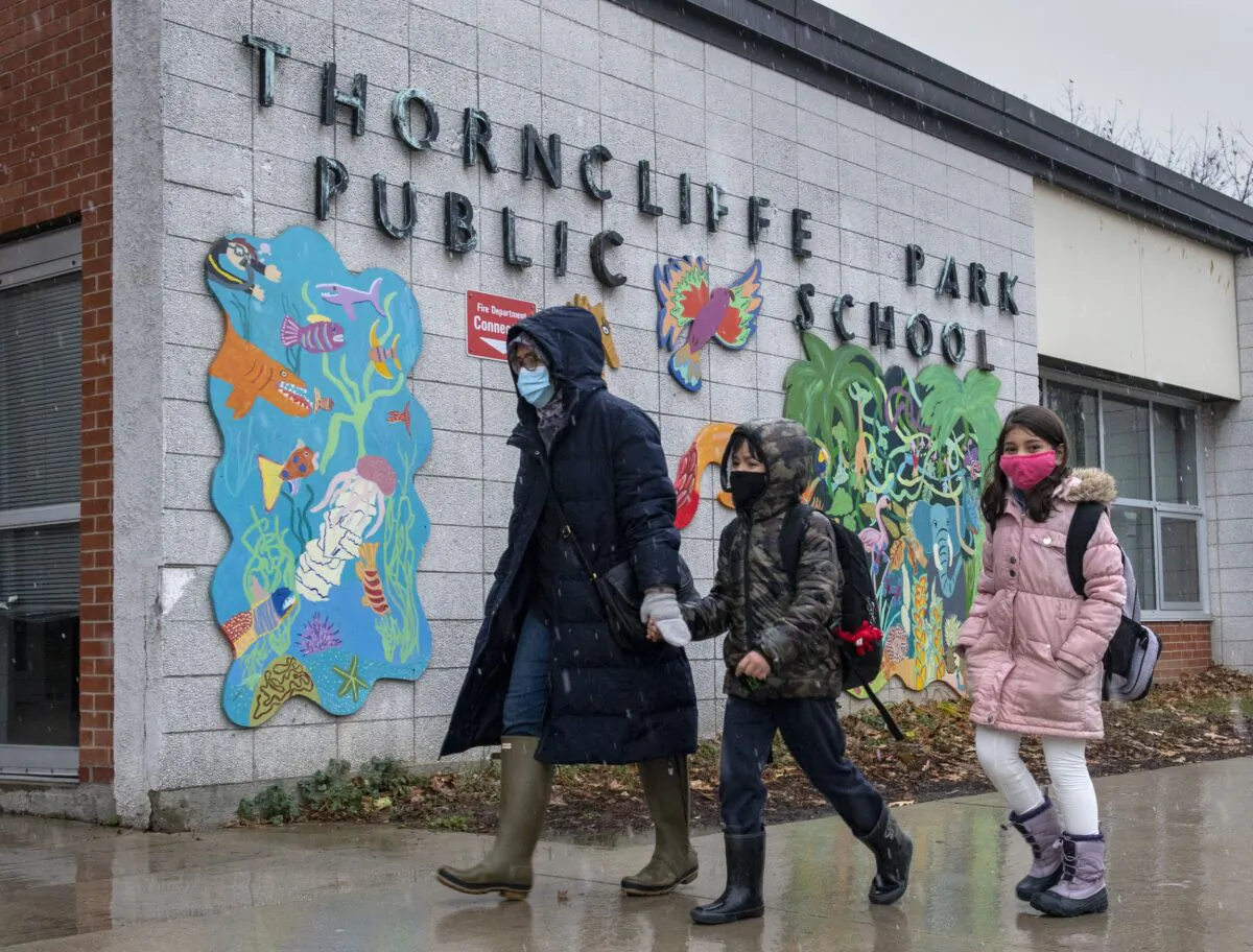A family walk past the sign at Thorncliffe Park Public School in Toronto on Dec. 4, 2020. (Frank Gunn/The Canadian Press)
