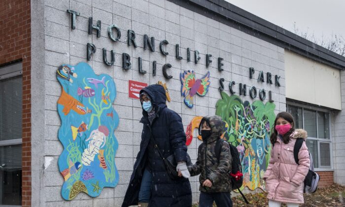 A family walk past the sign at Thorncliffe Park Public School in Toronto on Dec. 4, 2020. (Frank Gunn/The Canadian Press)