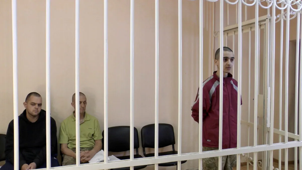 Britons Aiden Aslin, Shaun Pinner and Moroccan Brahim Saadoun captured by Russian forces during a military conflict in Ukraine, in a courtroom cage at a location given as Donetsk, Ukraine, in a still image from a video taken on June 8, 2022. (Supreme Court of Donetsk People's Republic/Handout via Reuters TV)