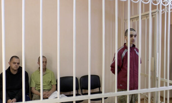 Britons Aiden Aslin, Shaun Pinner and Moroccan Brahim Saadoun captured by Russian forces during a military conflict in Ukraine, in a courtroom cage at a location given as Donetsk, Ukraine, in a still image from a video taken on June 8, 2022. (Supreme Court of Donetsk People's Republic/Handout via Reuters TV)
