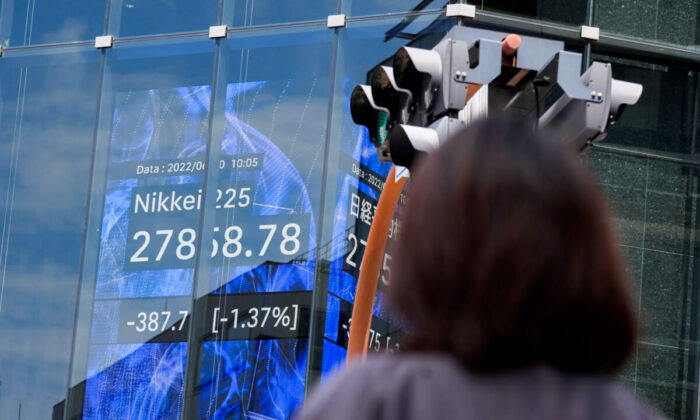 A woman stands in front of an electronic stock board showing Japan's Nikkei 225 index in Tokyo, Japan, on June 10, 2022.  (Eugene Hoshiko/AP Photo)