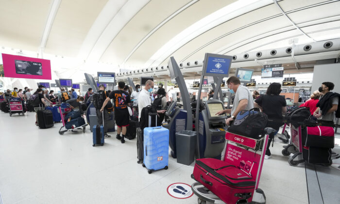 People wait in line to check in at Pearson International Airport in Toronto on May 12, 2022. (Nathan Denette/The Canadian Press)