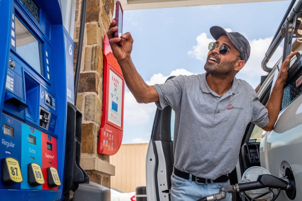 Guy Benhamou sends a picture of gas prices to friends while pumping gas at an Exxon Mobil station in Houston, Texas, on June 9, 2022. (Brandon Bell/Getty Images)