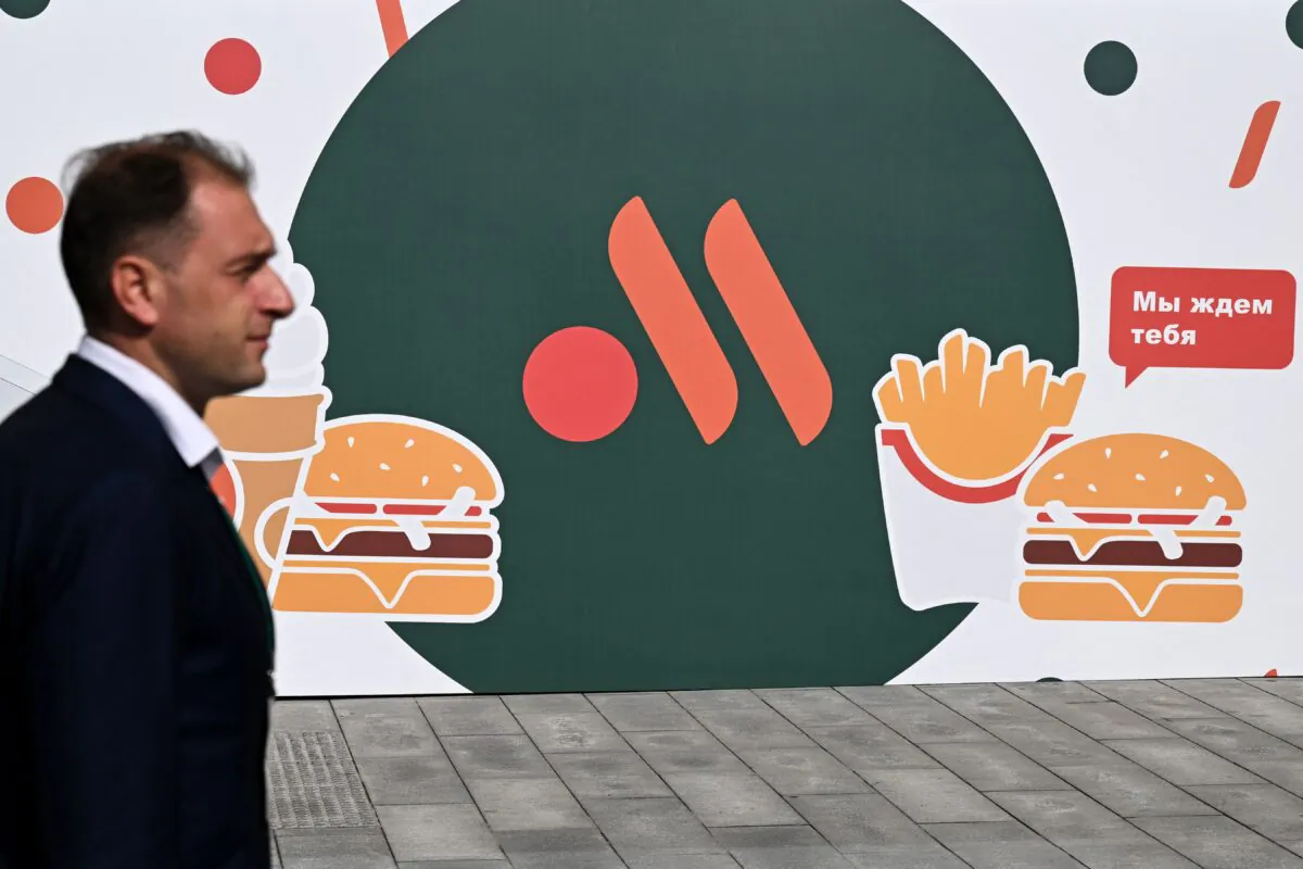 An employee stands in front of the new logo of the Russian version of a former McDonald's restaurant before the opening ceremony, in Moscow, on June 12, 2022. (Kirill Kudryavtsev/AFP via Getty Images)