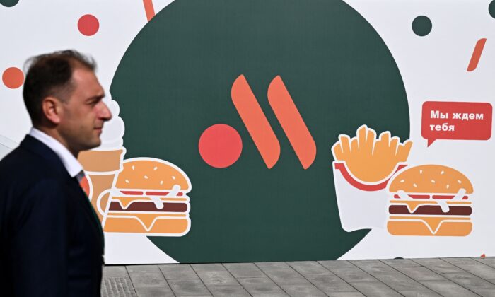 An employee stands in front of the new logo of the Russian version of a former McDonald's restaurant before the opening ceremony, in Moscow, on June 12, 2022. (Kirill Kudryavtsev/AFP via Getty Images)