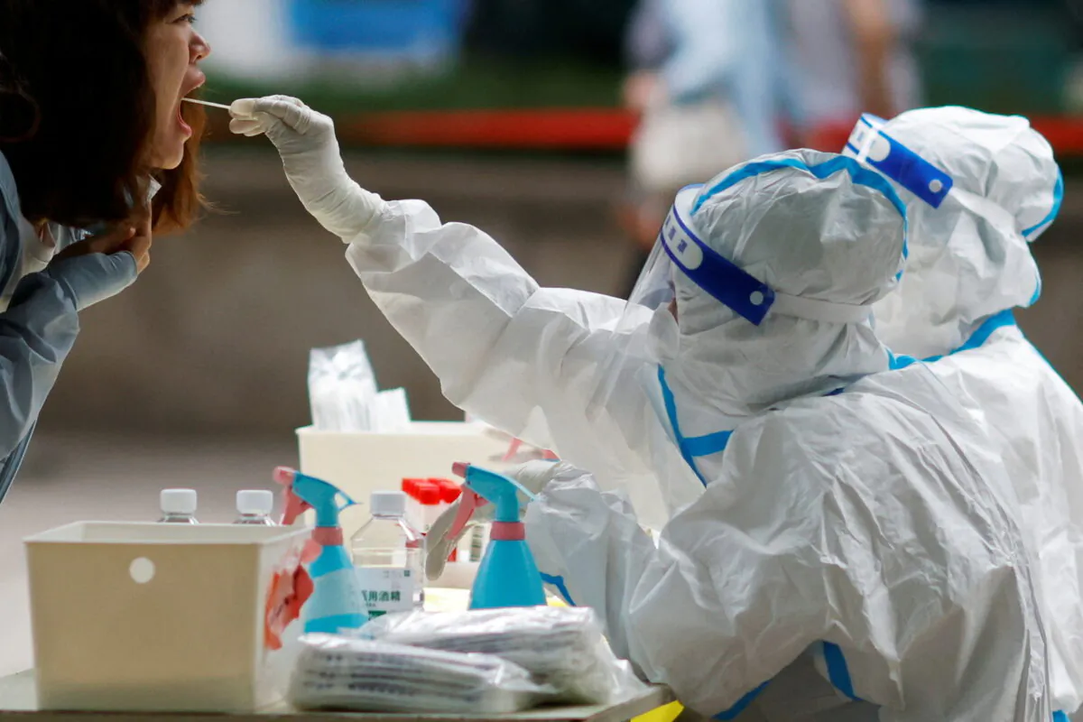 A medical worker in a protective suit collects a swab from a resident at a makeshift nucleic acid testing site, during a mass testing for COVID-19 in Chaoyang district of Beijing on June 13, 2022. (Carlos Garcia Rawlins/Reuters)