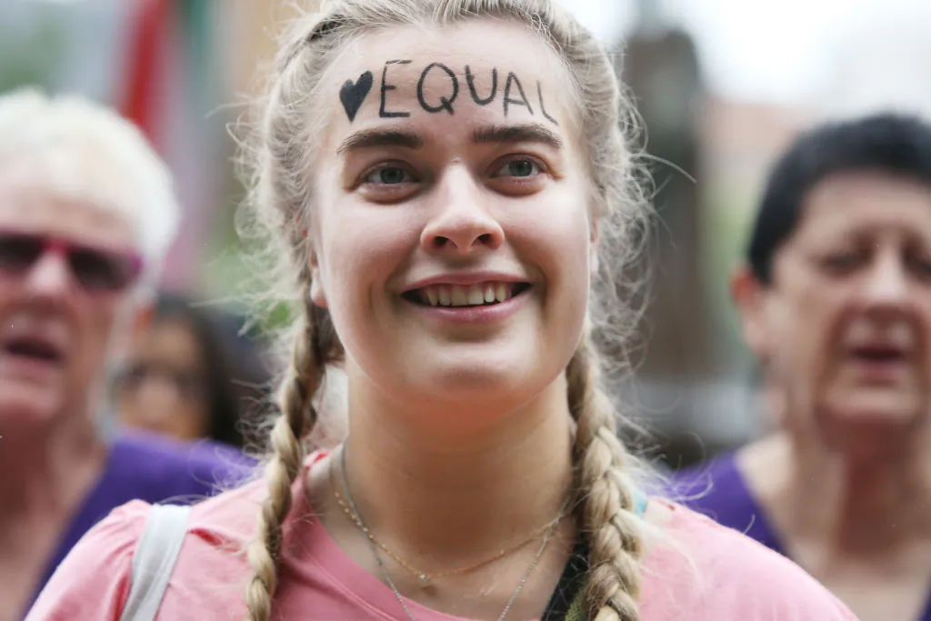 A woman smiles with the word "equal" written on her forehead as she gathers in Hyde Park during the International Women's Day march in Sydney, Australia, on March 7, 2020. (Lisa Maree Williams/Getty Images)