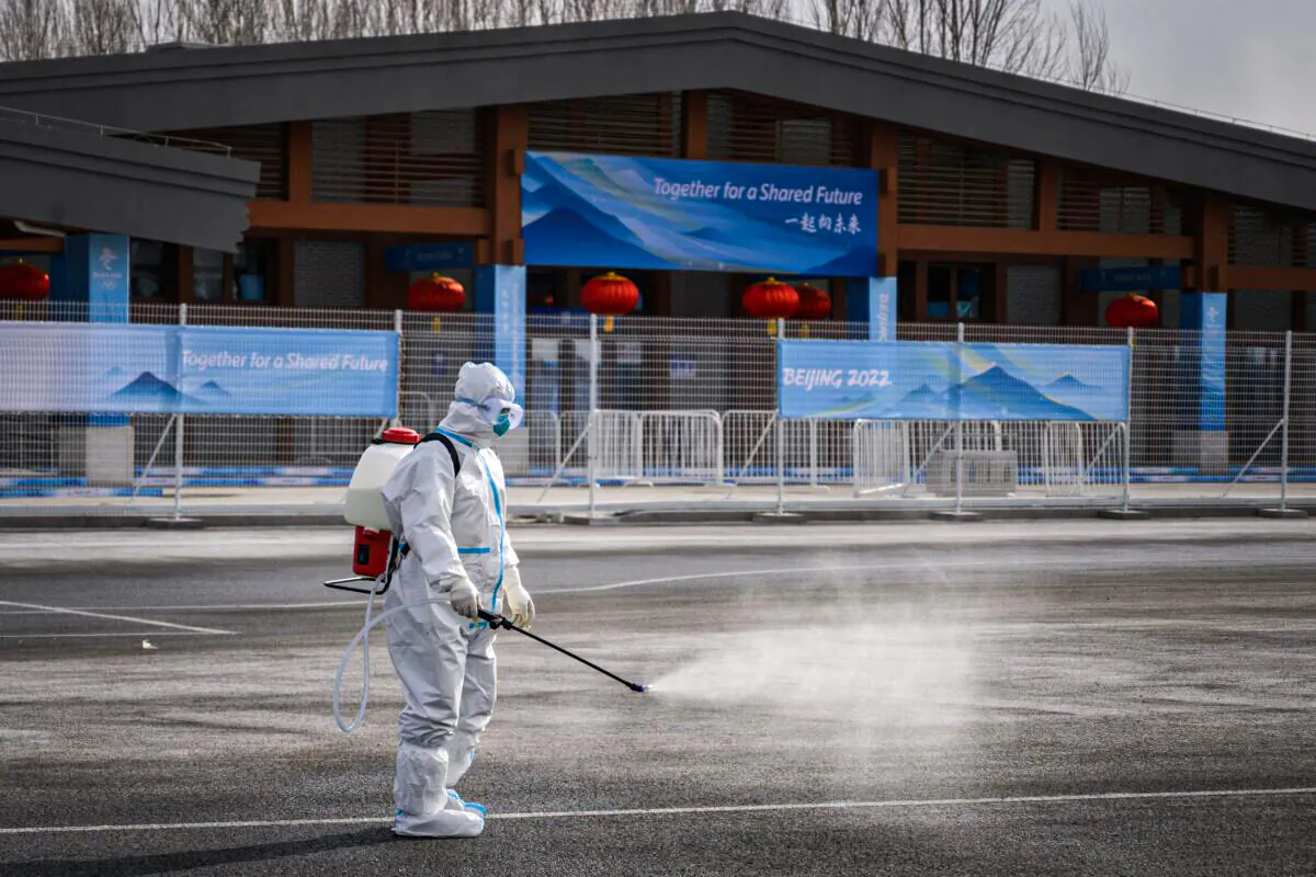A man in hazmat suit sprays disinfectant as a preventative measure against COVID-19 in a transport hub next to Yanqing that host the alpine skiing and sliding venues ahead of the 2022 Beijing Winter Olympics on Jan. 31, 2022. (FABRICE COFFRINI/AFP via Getty Images)