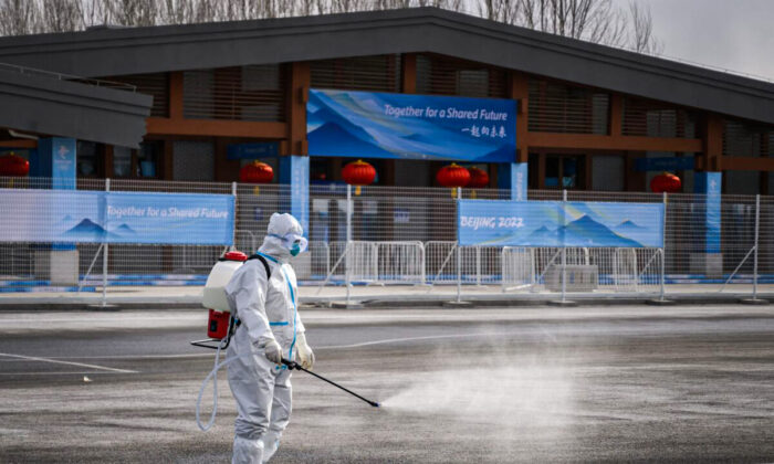 A man in hazmat suit sprays disinfectant as a preventative measure against COVID-19 in a transport hub next to Yanqing that host the alpine skiing and sliding venues ahead of the 2022 Beijing Winter Olympics on Jan. 31, 2022. (FABRICE COFFRINI/AFP via Getty Images)