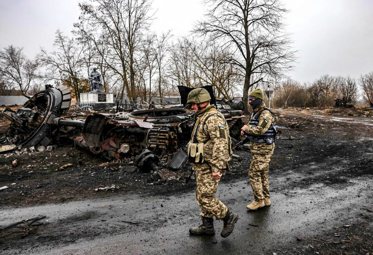 Ukrainian soldiers patrol next to a destroyed Russian tank in the village of Lukianivka near Kyiv, on March 30, 2022. (Ronaldo Schemidt/AFP via Getty Images)