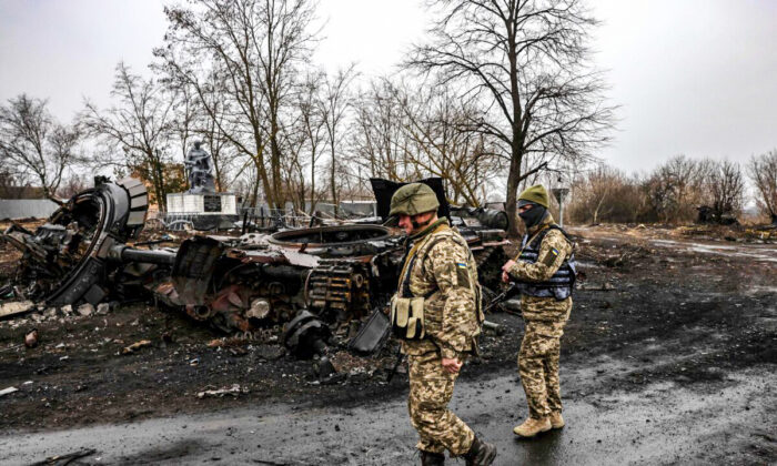 Ukrainian soldiers patrol next to a destroyed Russian tank in the village of Lukianivka near Kyiv, on March 30, 2022. (Ronaldo Schemidt/AFP via Getty Images)