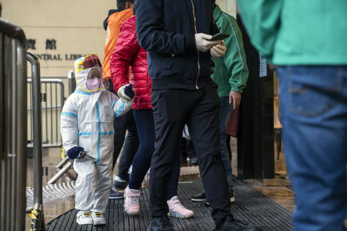 A child wearing personal protective equipment (PPE) enters a community vaccination center administering the Sinovac Biotech Ltd. COVID-19 vaccine to children and elderly in Hong Kong, China, on Feb. 23, 2022. (Chan Long Hei/Bloomberg)
