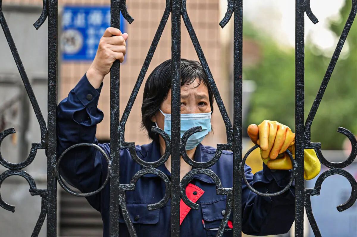 A worker looks past a fence in a compound during a COVID-19 lockdown in the Jing'an district of Shanghai, China, on May 25, 2022. (Hector Retamal/AFP via Getty Images)