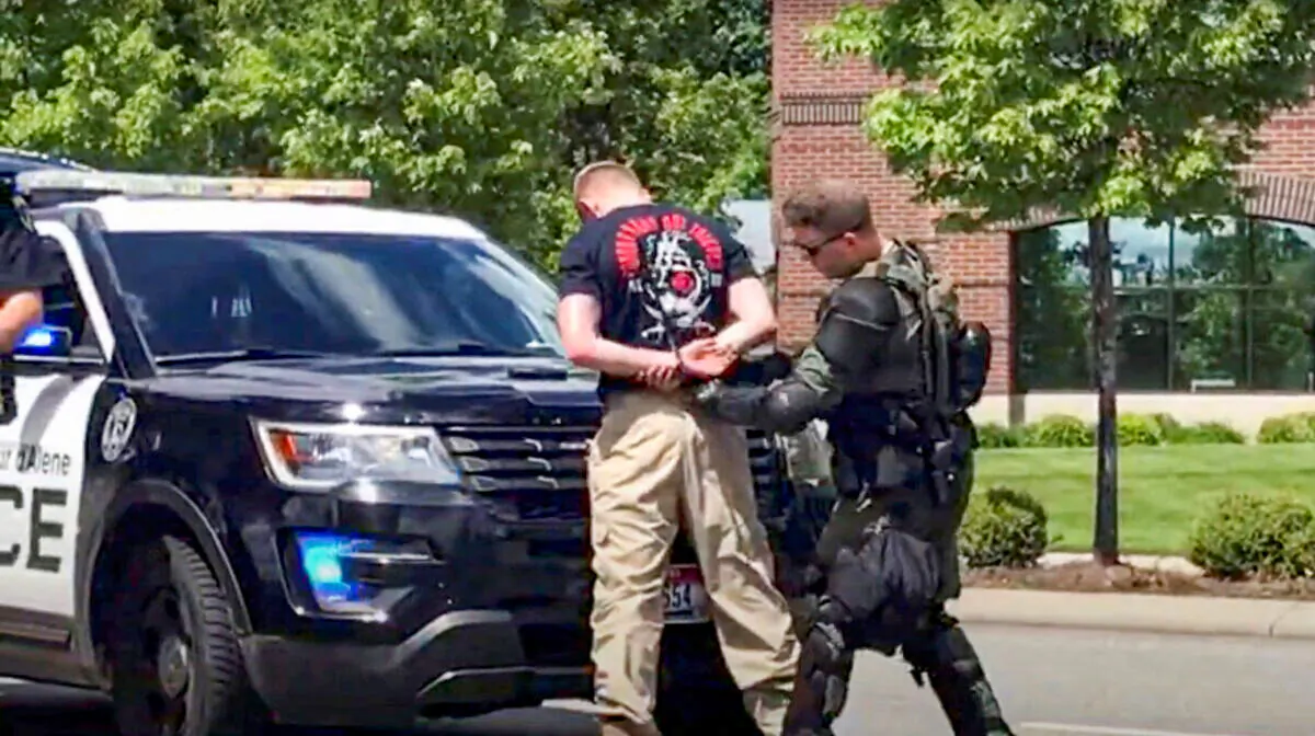 This still image obtained from a social media video shows a man affiliated with the Patriot Front group being detained by a police officer in riot gear on June 11, 2022. (North Country Off Grid/Youtube/via Reuters)