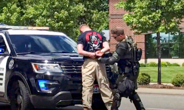 This still image obtained from a social media video shows a man affiliated with the Patriot Front group being detained by a police officer in riot gear on June 11, 2022. (North Country Off Grid/Youtube/via Reuters)
