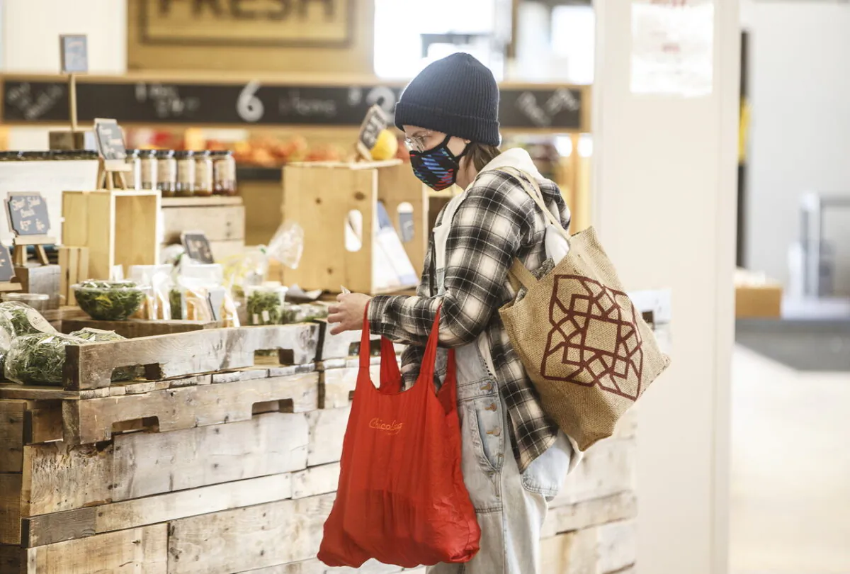 A shopper wearing a mask buys groceries at a sparse farmers market in Edmonton on March 22, 2020. (The Canadian Press/Jason Franson)
