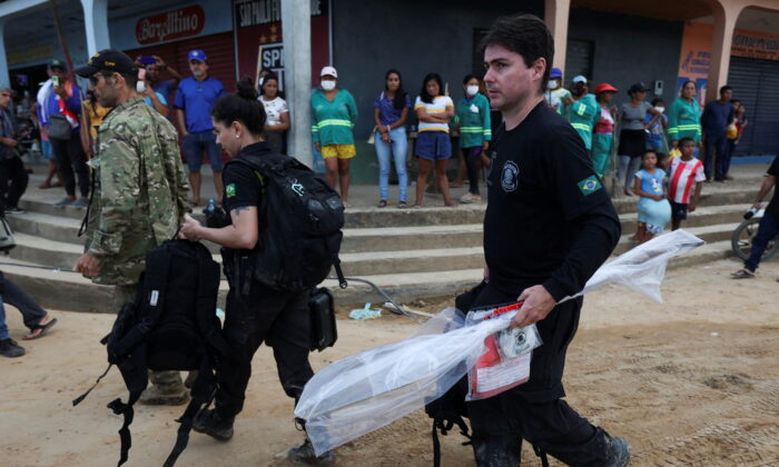 Federal Policemen carry seized material during a search operation for British journalist Dom Phillips and indigenous expert Bruno Pereira, who went missing while reporting in a remote and lawless part of the Amazon rainforest, near the border with Peru, in Atalaia do Norte, Amazonas state, Brazil, on June 14, 2022. (Bruno Kelly/PA Media)