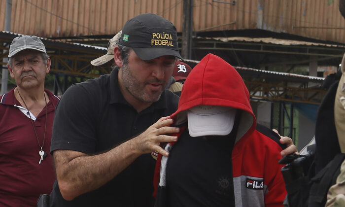 A federal police officer escorts a suspect towards a river in the area where Indigenous expert Bruno Pereira and freelance British journalist Dom Phillips disappeared, in Atalaia do Norte, Amazonas state, Brazil, on June 15, 2022. (Edmar Barros/AP Photo)