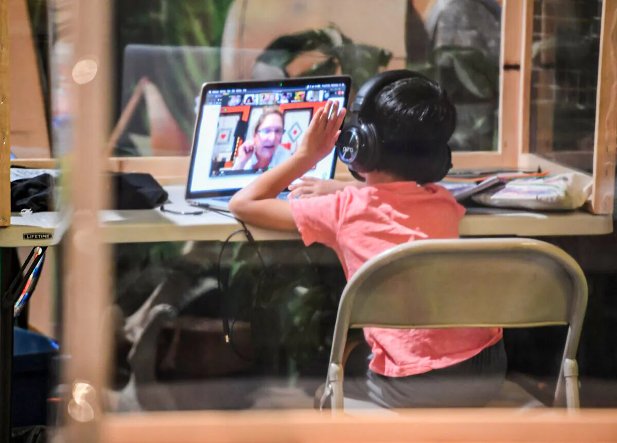 A student follows along remotely with their regular school teacher's online live lesson from a desk separated from others by plastic barriers in California on Sept. 10, 2020. (Robyn Beck/AFP via Getty Images)