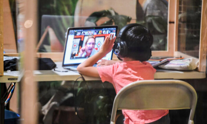 A student follows along remotely with their regular school teacher's online live lesson from a desk separated from others by plastic barriers at STAR Eco Station Tutoring & Enrichment Center on September 10, 2020 in Culver City, California. - California public school students will continue to learn at home, in private learning pods, or at specialized enrichment centers like Star Eco Station as the coronavirus pandemic continues, after a lawsuit brought by the Orange County Board of Education seeking to compel the state to reopen public schools was shot down by the California Supreme Court on September 10. (Photo by Robyn Beck / AFP) (Photo by ROBYN BECK/AFP via Getty Images)