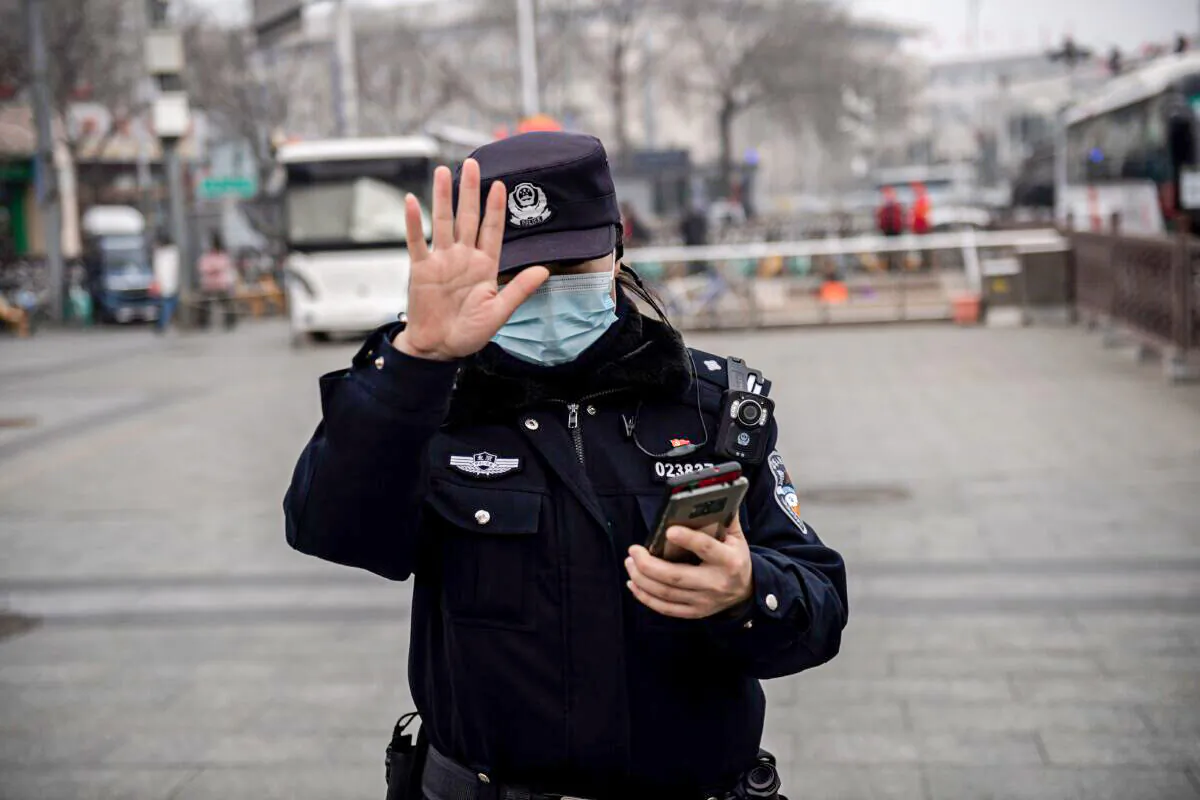 A police officer gestures to a journalist not to photograph in Beijing, on March 5, 2021. (Nicolas Asfouri/AFP via Getty Images)