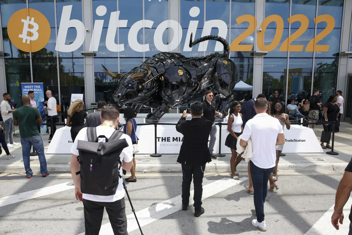 Attendees pose for photos in front of The Miami Bull during the Bitcoin 2022 Conference at Miami Beach Convention Center on April 7, 2022. (Marco Bello/Getty Images)