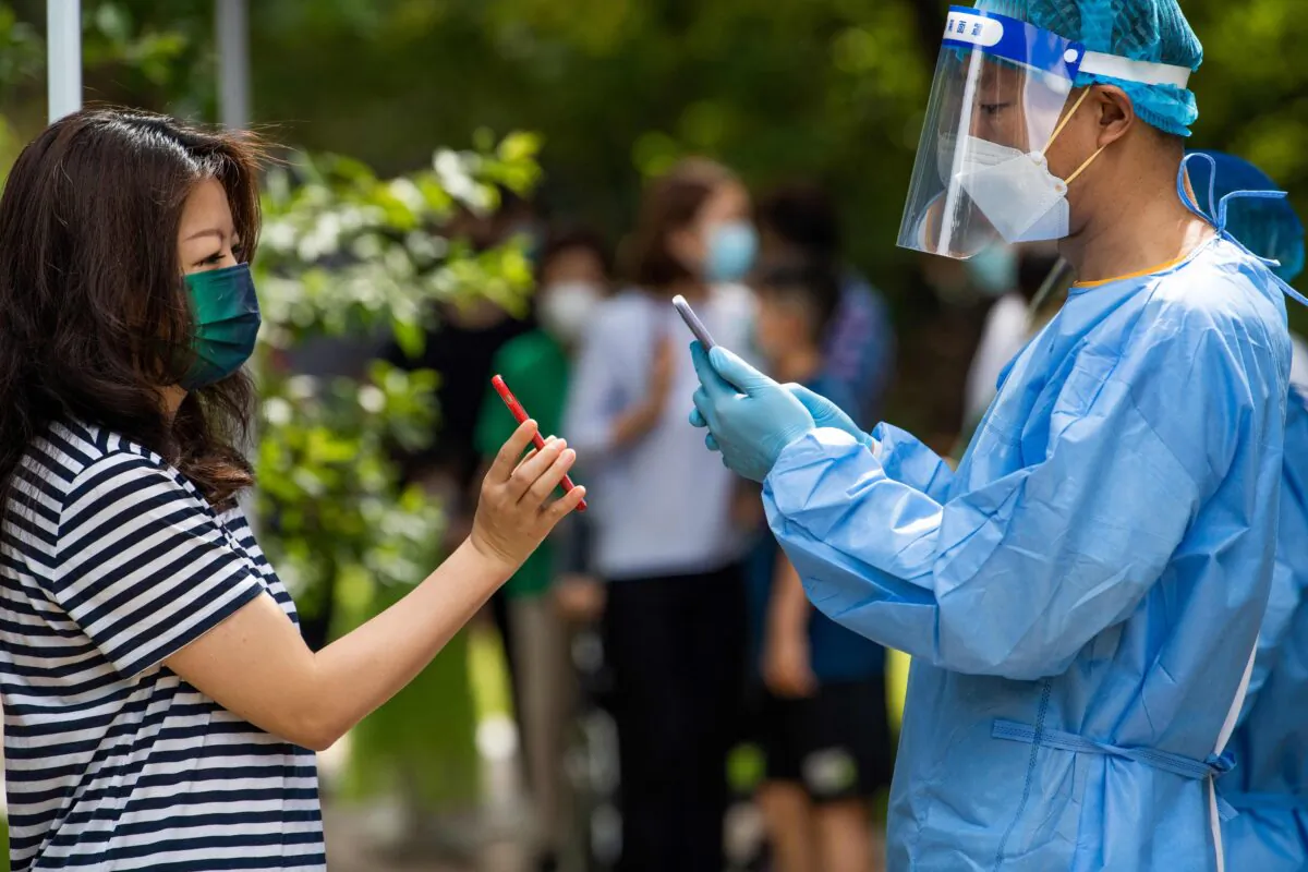 A health worker scans the health code of a local resident for COVID-19 test results in the Pudong district of Shanghai on June 11, 2022. (Liu Jin/AFP via Getty Images)