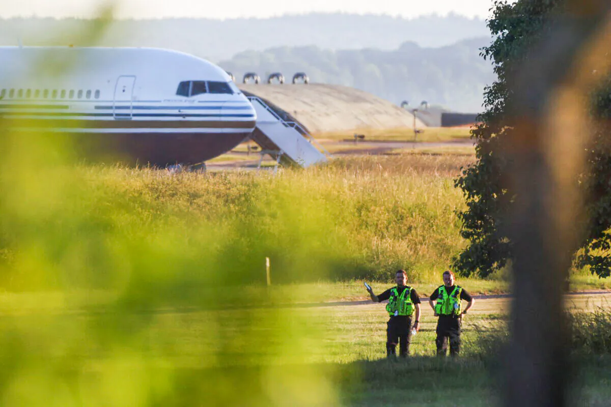 Police officers stand near a plane reported by British media to be first to transport illegal immigrants to Rwanda at MoD Boscombe Down base in Wiltshire, England, on June 14, 2022. (Hannah McKay /Reuters)