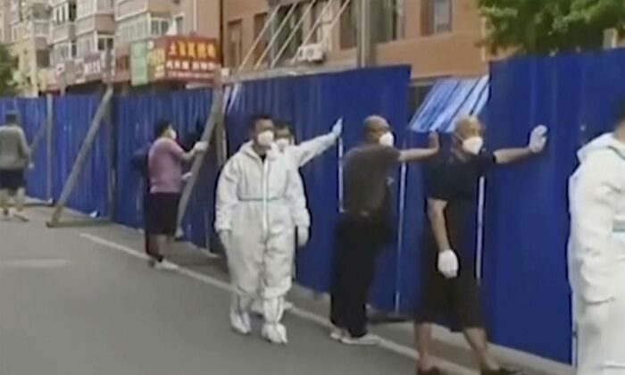 2022年6月13日，在中国东北辽宁省丹东市，工人们在一个被封锁的社区周围设置了围栏。（DOUYIN@91244624 via AP）