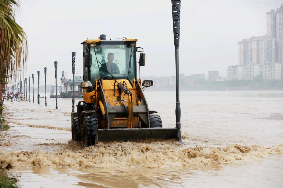 A worker using a bulldozer to clear a flooded street caused by heavy rains in Rongan in China's southern Guangxi region on June 5, 2022. (STR/AFP via Getty Images)