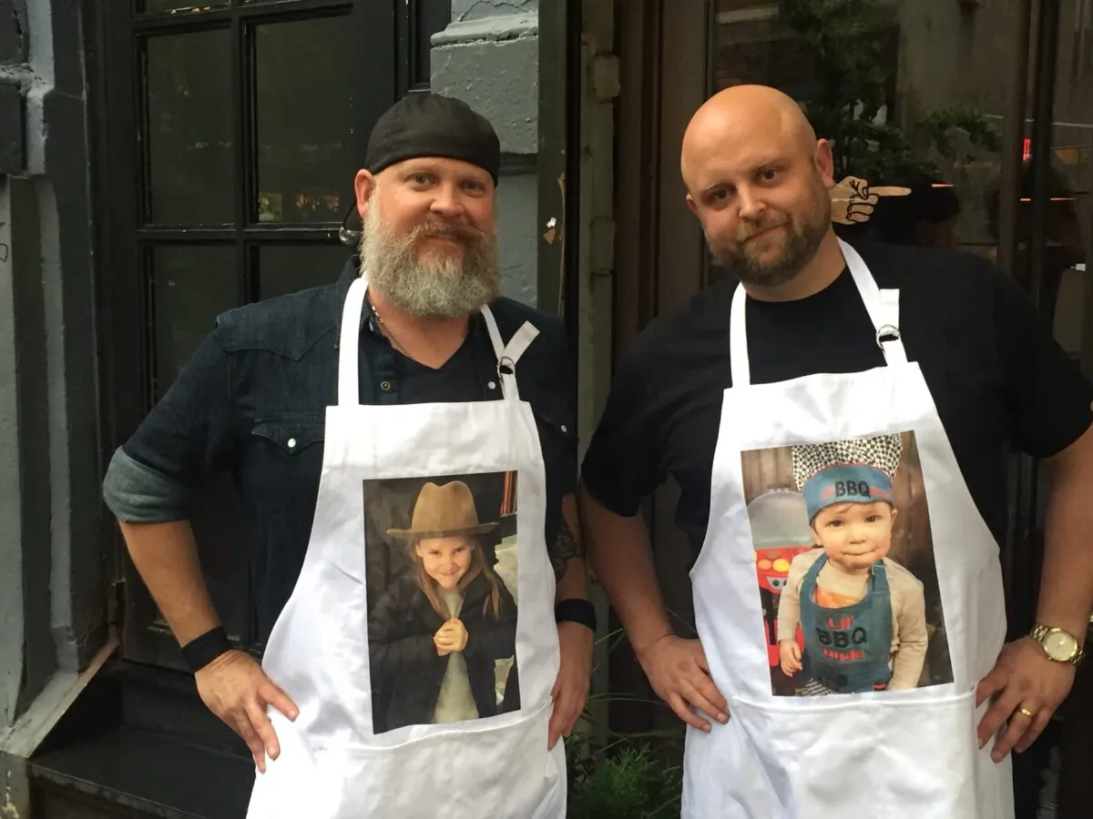 Anderson (R) and Fey rep their kids on custom aprons. (Courtesy of The Grill Dads)
