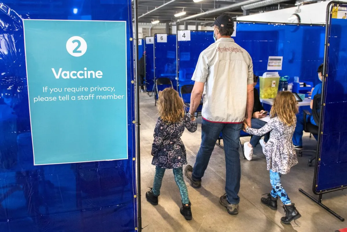 A man arrives with two young girls for his shot at the COVID-19 vaccination clinic at the Ontario Food Terminal in Toronto on May 11, 2021. (Frank Gunn/The Canadian Press)
