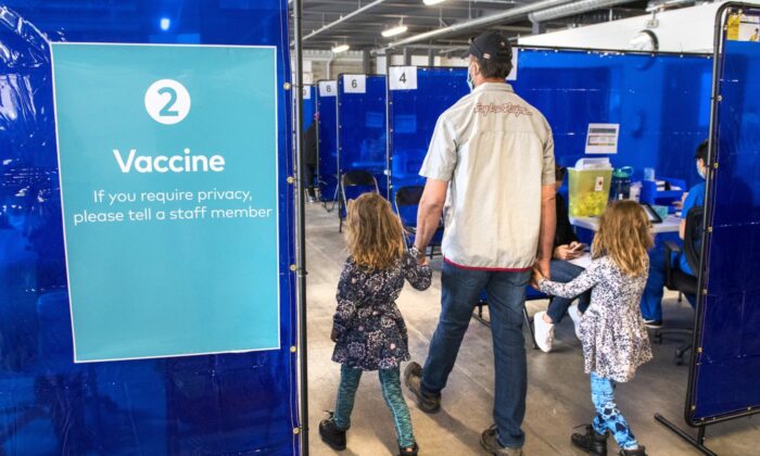 A man arrives with two young girls for his shot at the COVID-19 vaccination clinic at the Ontario Food Terminal in Toronto on May 11, 2021. (Frank Gunn/The Canadian Press)