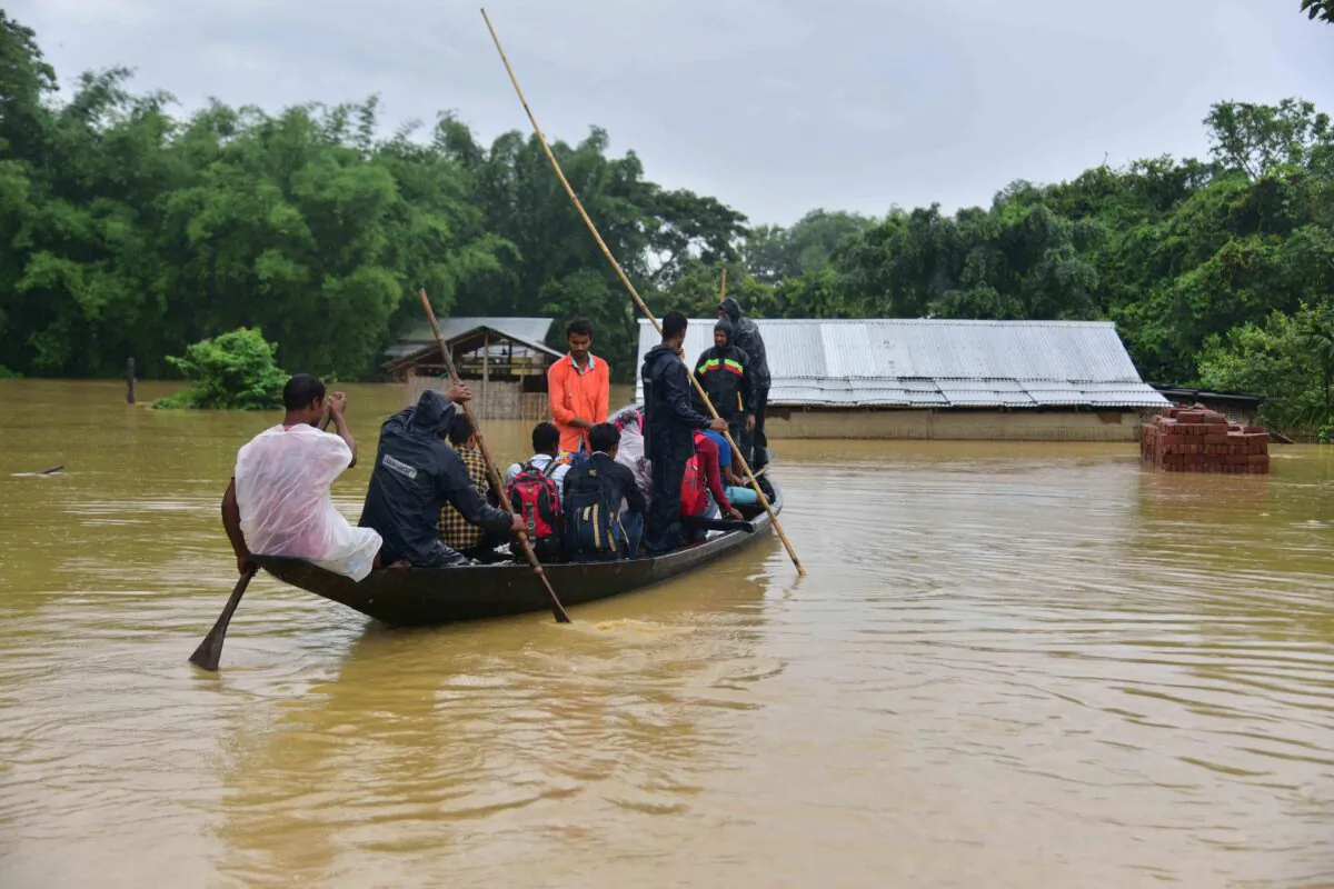 People travel on a boat through flood waters following heavy monsoon rainfalls in the Nagaon district in Assam, India, on June 18, 2022. (Biju Boro/AFP via Getty Images)