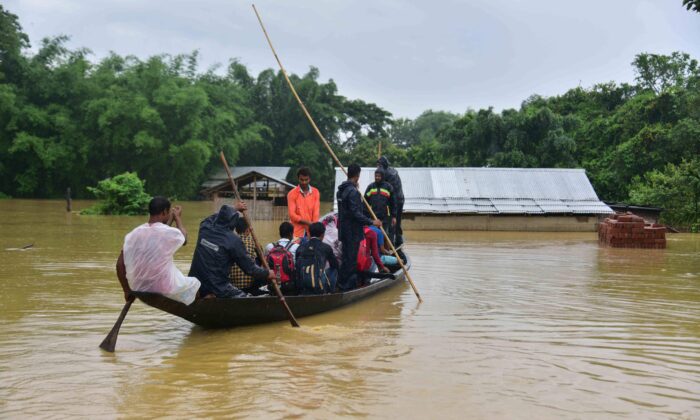 People travel on a boat through flood waters following heavy monsoon rainfalls in the Nagaon district in Assam, India, on June 18, 2022. (Biju Boro/AFP via Getty Images)