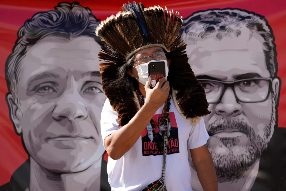 Indigenous leader Kamuu Wapichana is backdropped by a banner that shows images of missing freelance British journalist Dom Phillips (L) and Indigenous expert Bruno Pereira, during a protest asking authorities to expand the search efforts for the two men, in front of the Ministry of Justice in Brasilia, Brazil, on June 14, 2022. (Eraldo Peres/AP Photo)