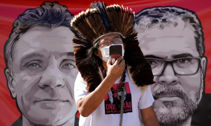 Indigenous leader Kamuu Wapichana is backdropped by a banner that shows images of missing freelance British journalist Dom Phillips (L) and Indigenous expert Bruno Pereira, during a protest asking authorities to expand the search efforts for the two men, in front of the Ministry of Justice in Brasilia, Brazil, on June 14, 2022. (Eraldo Peres/AP Photo)
