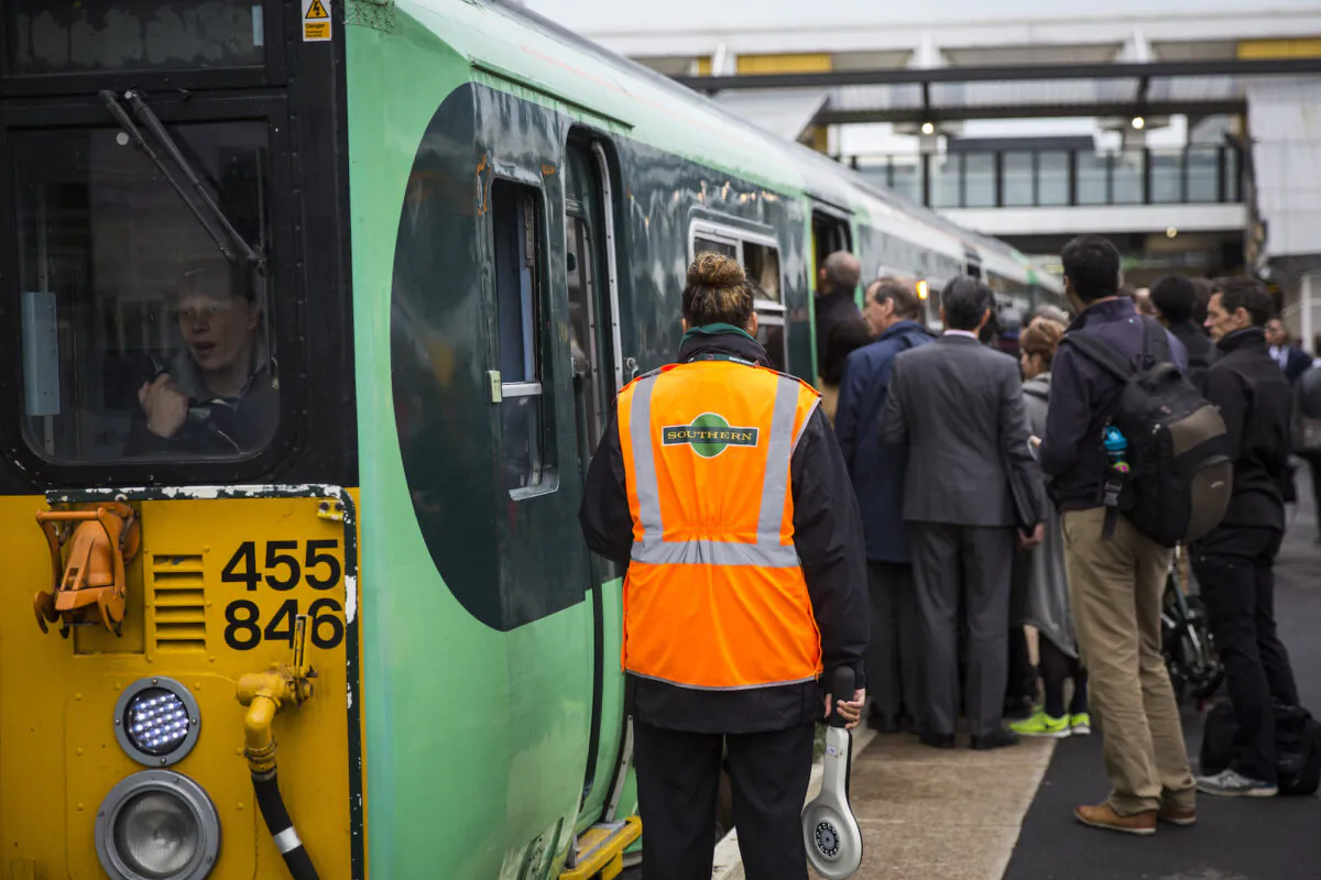 A rail conductor waits as commuters board a train at East Croydon station on Oct. 18, 2016. (Jack Taylor/Getty Images)