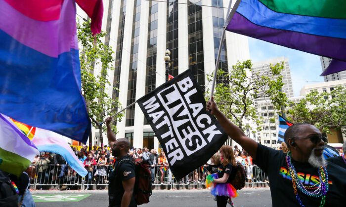 2017 年 6 月在加利福尼亚州旧金山举行的骄傲游行中，男子挥舞着彩虹和黑人的命也是命旗帜。  （以利亚·努维拉奇/盖蒂图片社）