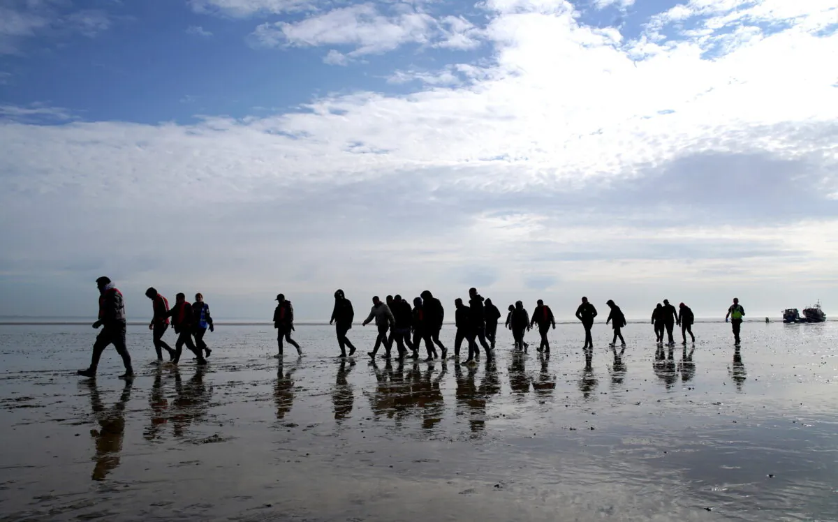 A group of people thought to be illegal immigrants walk up the beach after being brought onboard the RNLI Dungeness Lifeboat in to Dungeness, Kent, on May 17, 2022. (Gareth Fuller/PA Media)