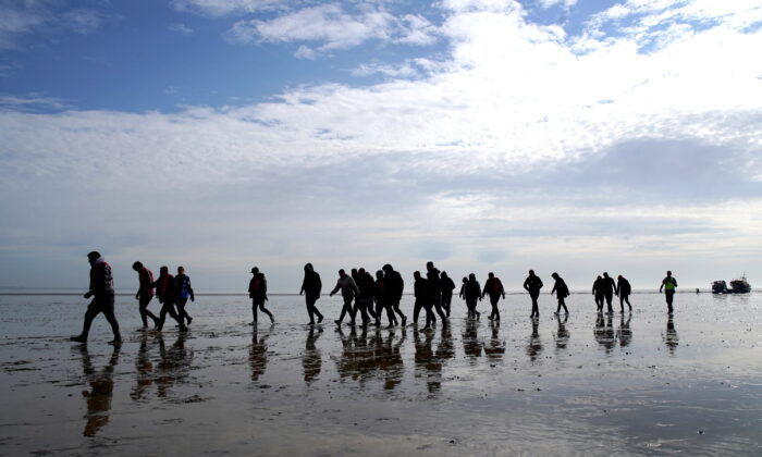 A group of people thought to be illegal immigrants walk up the beach after being brought onboard the RNLI Dungeness Lifeboat in to Dungeness, Kent, on May 17, 2022. (Gareth Fuller/PA Media)