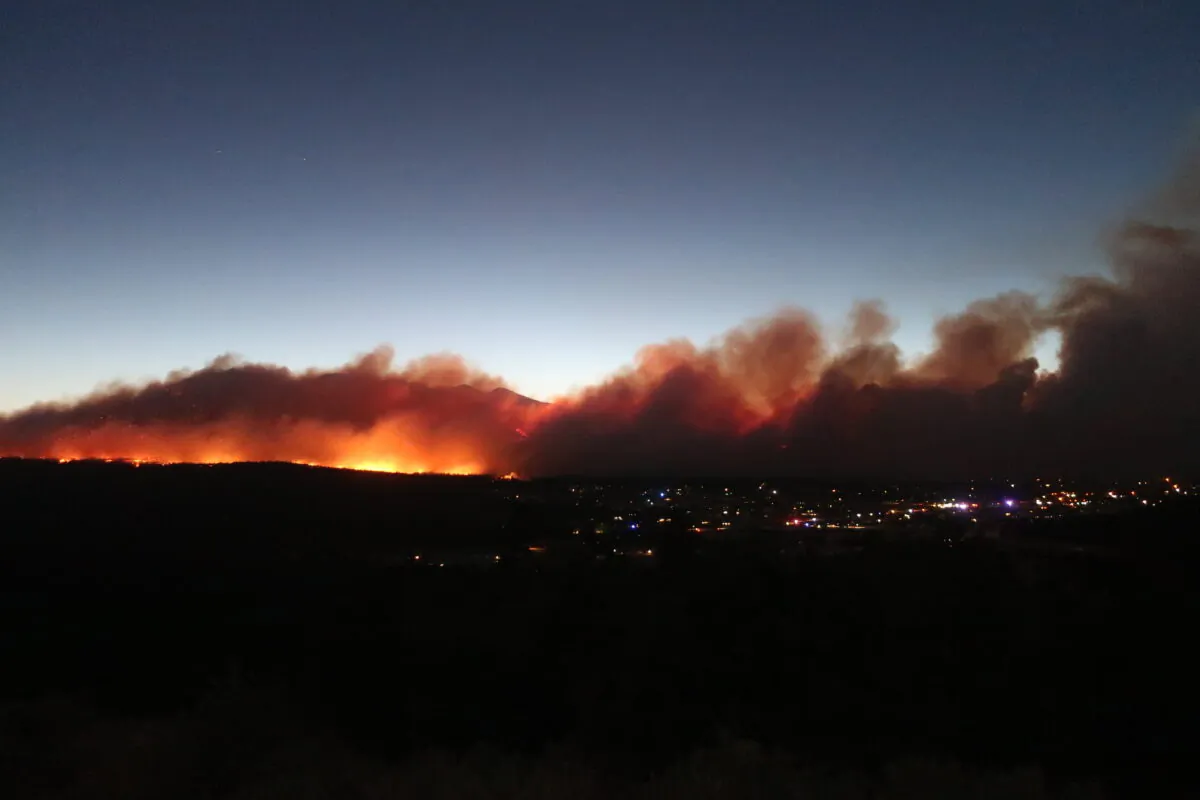 A wildfire burning casts a glow above neighborhoods on the outskirts of Flagstaff, Ariz., on June 12, 2022. (Felicia Fonseca/AP Photo)