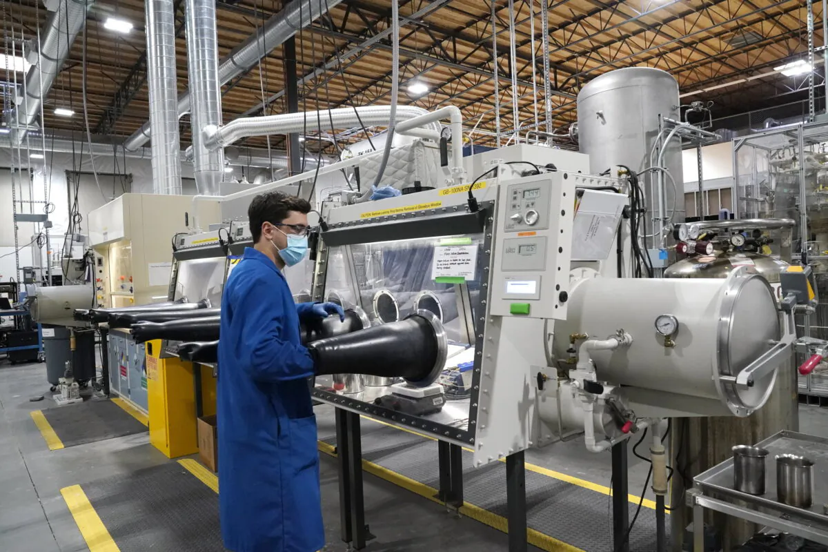 Test engineer Jacob Wilcox pulls his arm out of a glove box used for processing sodium at TerraPower, a company developing and building small nuclear reactors in Everett, Wash., on Jan. 13, 2022. (Elaine Thompson/AP Photo)
